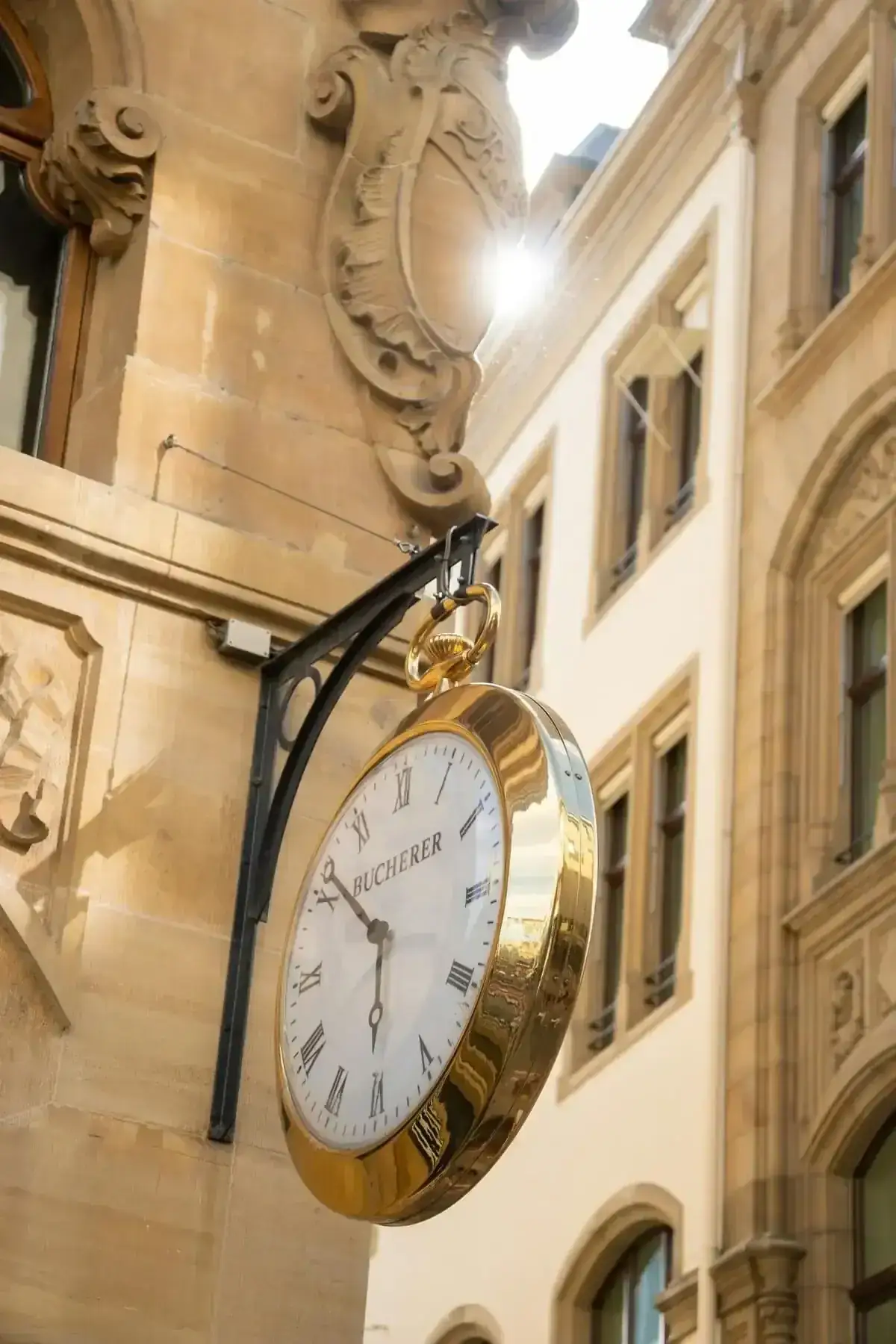 Golden Bucherer clock on a historic facade in Basel's charming city center.