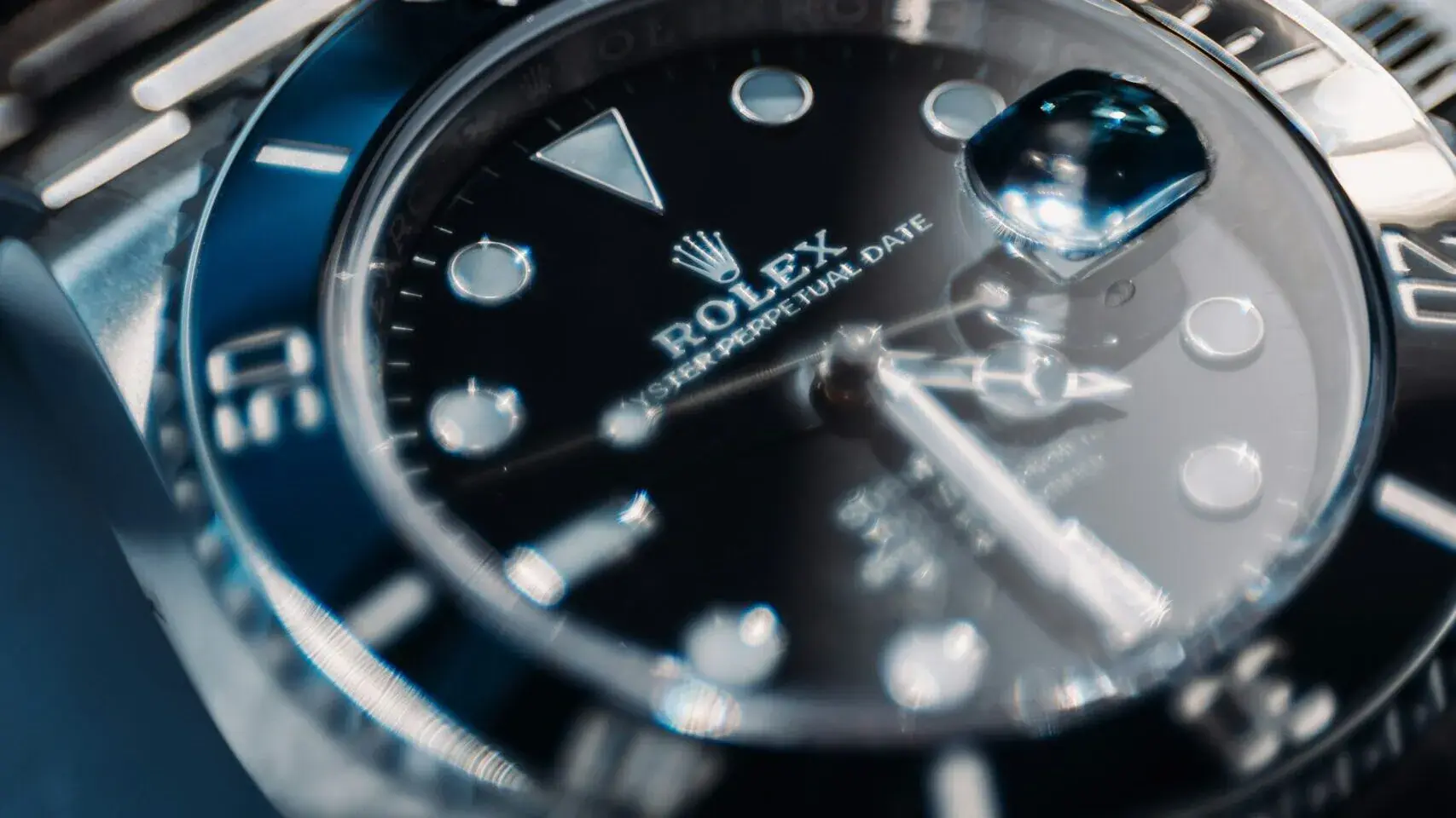 Gros plan d'une montre-bracelet Rolex de luxe avec cadran noir, index lumineux et bracelet métallique - une icône de l'histoire et de la légende horlogère - montrant la loupe de la date et la lunette détaillée sous une lumière douce se reflétant sur le cadran de la montre.