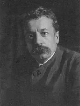 Portrait en noir et blanc de René Lalique, un homme d'âge moyen aux cheveux ondulés et à la grosse moustache broussailleuse. Il porte une veste boutonnée à col montant et regarde sérieusement l'appareil photo sur un fond sombre et uni.