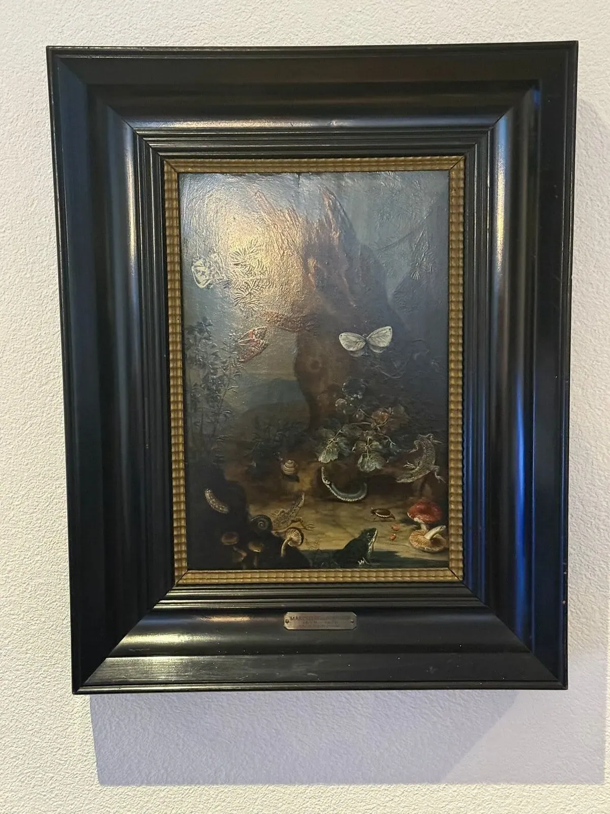 Peinture encadrée avec nature morte sur un mur.