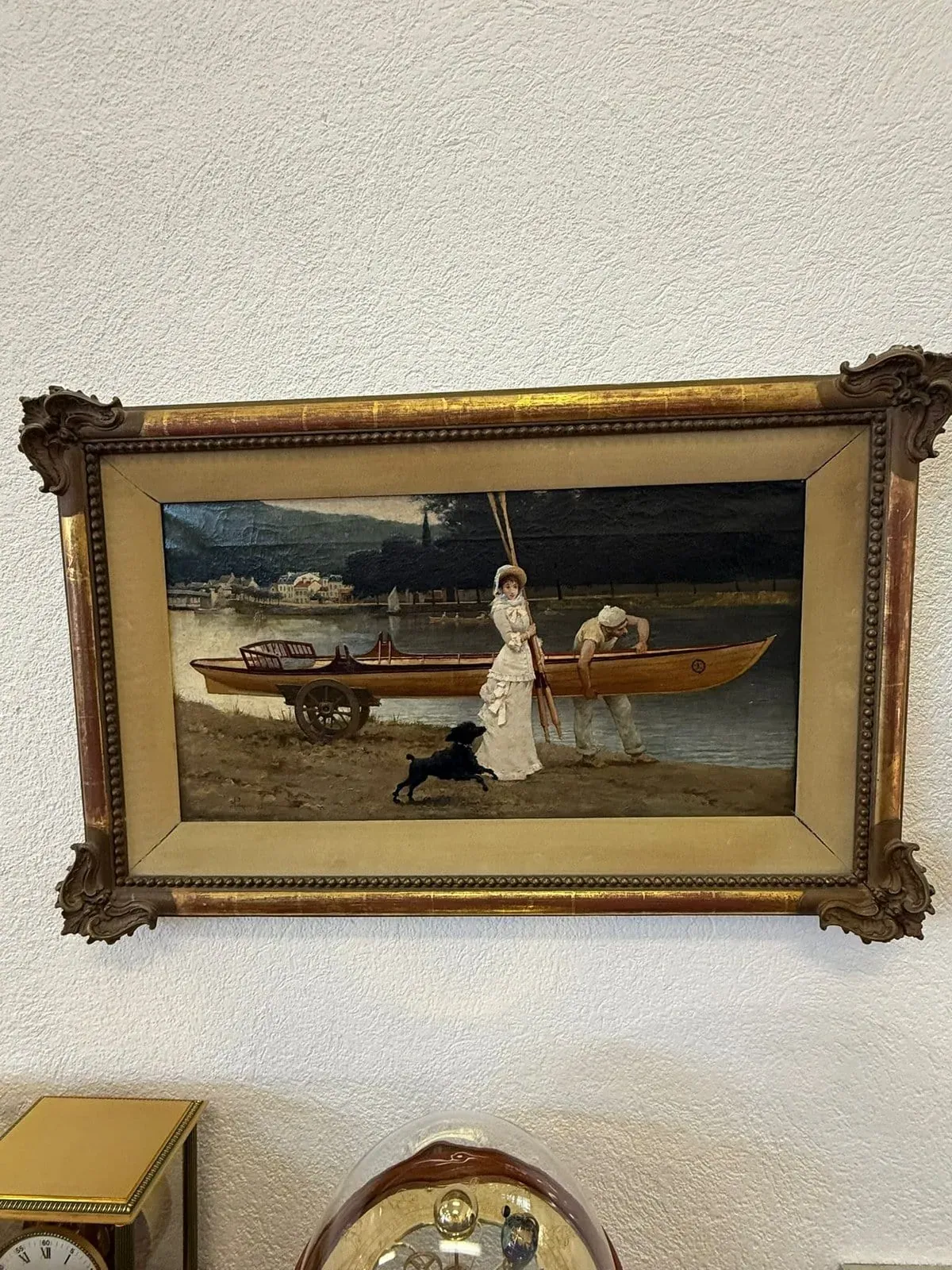 Un tableau encadré représente une femme en tenue victorienne avec un parasol, un homme en vêtements blancs à côté d'un bateau en bois et un chien noir au bord d'une rivière près de Thônex. Le cadre orné est accroché à un mur texturé sous un ciel clair.
