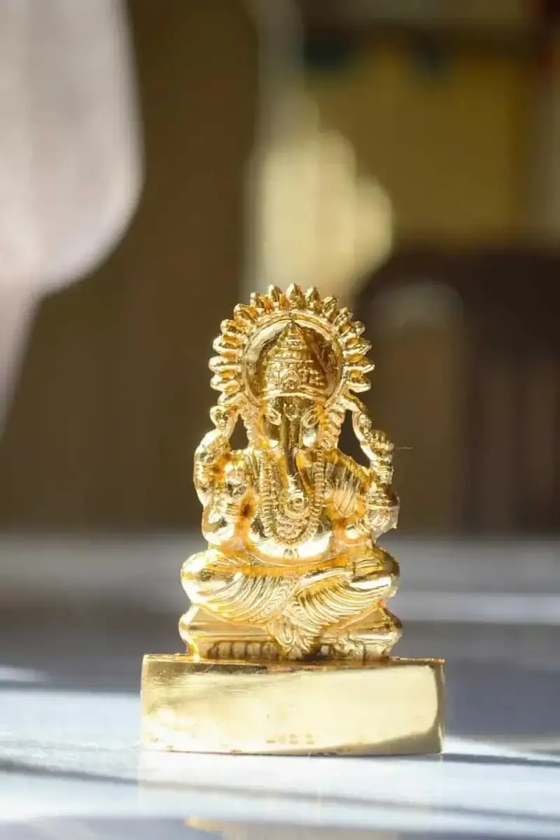 Close-up of a gold Ganesh figurine in warm indoor lighting, capturing its intricate details.