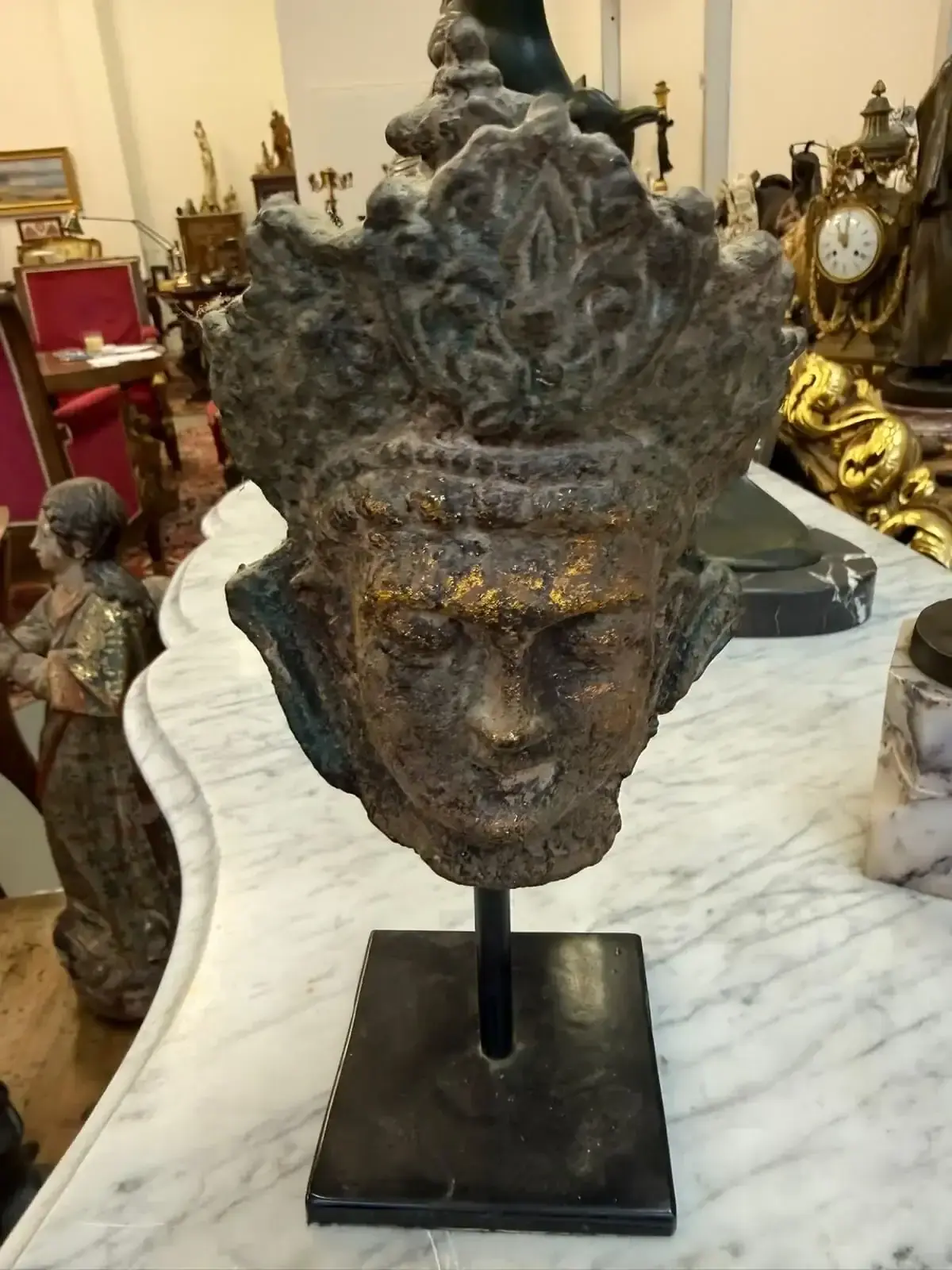 Tête de statue antique exposée sur un socle.