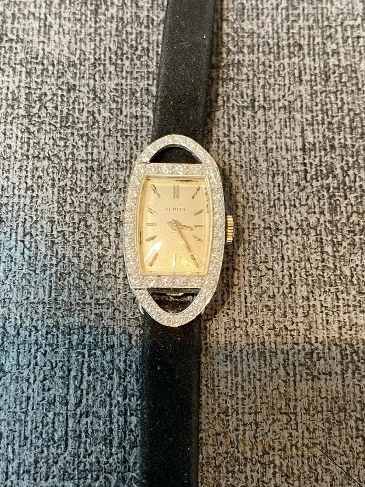 Montre dorée à bracelet noir sur fond texturé