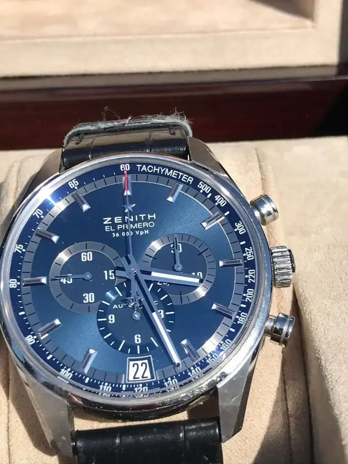 Montre chronographe bleue avec bracelet en cuir noir.
