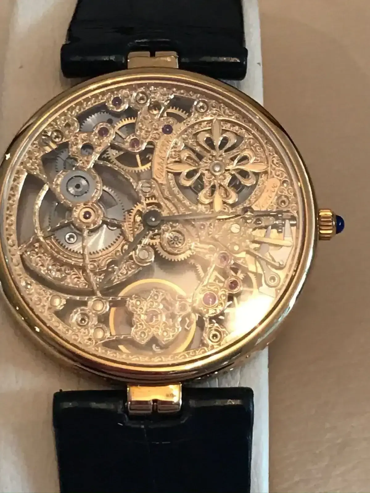 Montre squelette dorée avec bracelet noir.