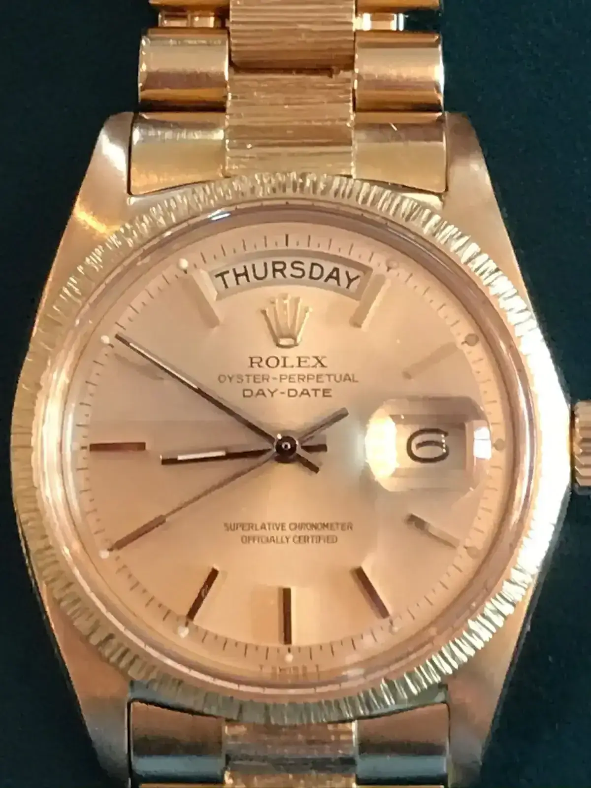 Montre dorée affichant la date et le jour.