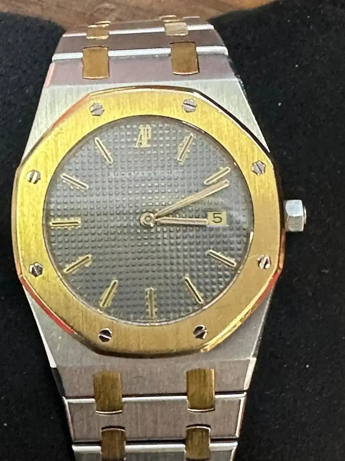 Montre argentée et dorée avec cadran gris.