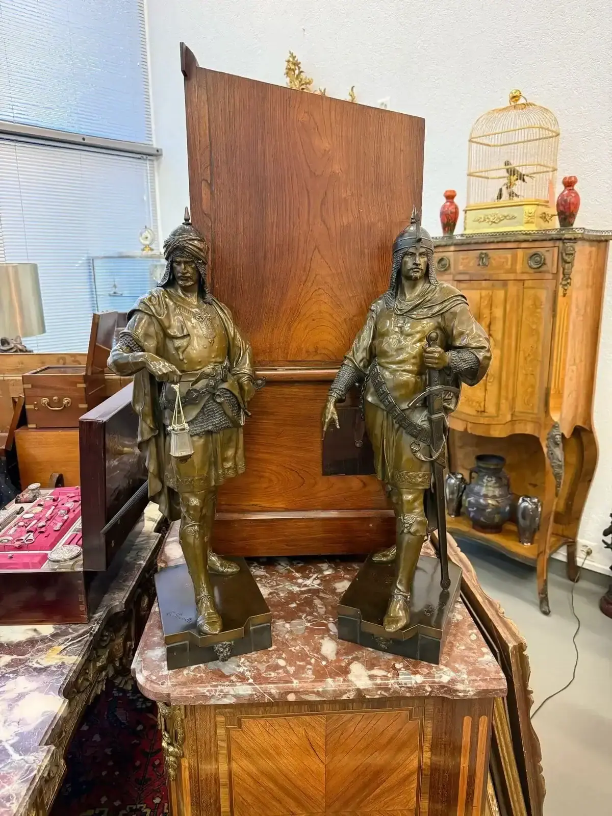 Statues en bronze de guerriers sur meuble ancien.